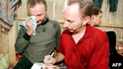 FILE - Risto Vahanan and Werner Wellert write a note while being held hostage at the Abu Sayyaf camp in the Philippines, May 1, 2000. On Oct. 21, 2024, a Philippine court convicted and sentenced to life 17 Islamic militants for the kidnapping.