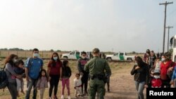 Familias inmigrantes solicitantes de asilo esperan ser transportadas por la Patrulla Fronteriza de EE. UU. en La Joya, Texas, después de cruzar el Río Grande desde México en abril de 2021.