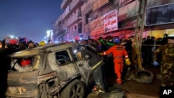 Sejumlah petugas berkumpul di dekat mobil yang terbakar akibat serangan drone AS di timur Kota Baghdad, Irak, pada 7 Februari 2024. (Foto: AP/Hadi Mizban)