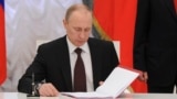 Russian President Vladimir Putin prepares to sign a law on ratification of a treaty making Crimea part of Russia, during a ceremony in Moscow's Kremlin in Moscow, March 21, 2014. 