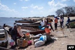 La gente llega a la costa desde la mina ilegal colapsada, en Puerto Guacara en La Paragua, estado Bolívar, Venezuela, el 22 de febrero de 2024. (Foto de Ronald PEÑA/AFP)