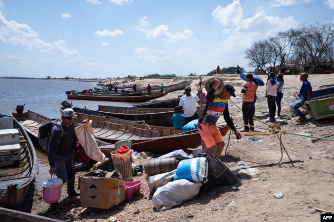 La gente llega a la costa desde la mina ilegal colapsada, en Puerto Guacara en La Paragua, estado Bolívar, Venezuela, el 22 de febrero de 2024. (Foto de Ronald PEÑA/AFP)