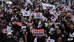 Simpatizantes del destituido presidente surcoreano Yoon Suk Yeol agitan banderas de Corea del Sur frente a una corte que celebró una audiencia el 18 de enero de 2025 para determinar si continúa detenido durante la investigación que se le sigue por declarar la ley marcial.