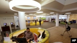 FILE - Northeastern University graduate student Shabbir Hussain, of Indore, India, left, views a computer screen at the entrance to the Snell Library on the Northeastern University campus in Boston on May 24, 2016. 