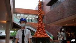 A security guard stands in front of the "Pillar of Shame" statue, a memorial for those killed in the 1989 Tiananmen crackdown, at the University of Hong Kong, Oct. 13, 2021. (AP Photo/Kin Cheung)