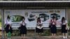 Students from Chulalongkorn University wear face masks to protect themselves from poor air quality as they wait at a bus stop in Bangkok, Thailand, Monday, Jan. 20, 2020. Thick haze blanketed the Thai capital on Monday sending air pollution levels…