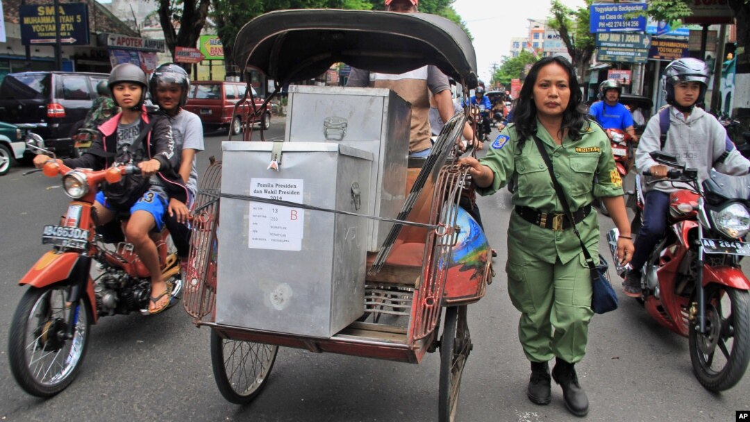 Seorang petugas mengawal becak yang membawa kotak-kotak suara untuk didistribusikan ke TPS-TPS di Yogyakarta (8/7).