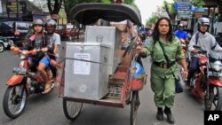 Seorang petugas mengawal becak yang membawa kotak-kotak suara untuk didistribusikan ke TPS-TPS di Yogyakarta (8/7).