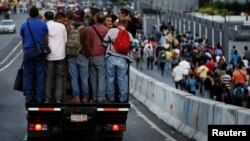 FILE - People ride in a truck and walk on a street during a blackout in Caracas, Venezuela, Feb. 6, 2018. 