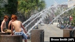 Anak-anak yang kepanasan beristirahat sejenak di air mancur di Waterfront Park di Charleston, pantai Carolina Selatan. (Foto: AP/Bruce Smith)