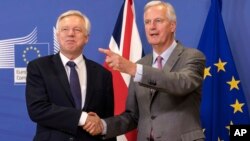 FILE - EU chief Brexit negotiator Michel Barnier, right, welcomes British Secretary of State David Davis for a meeting at the EU headquarters in Brussels, July 17, 2017. The British government is fighting back against criticisms that it is divided and unp