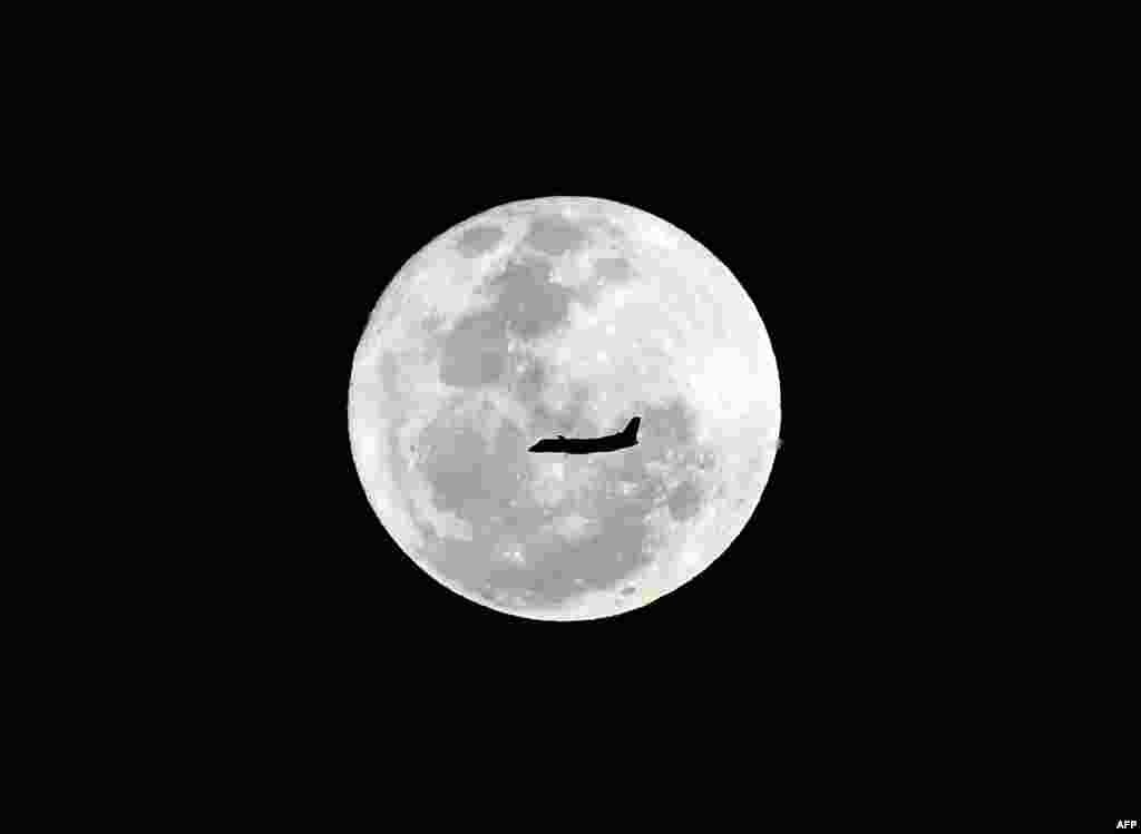 A plane flies in front of a full moon in Sydney, Australia.