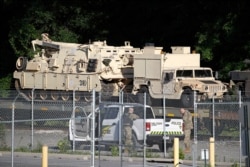 Military police stand military vehicles on a flat car in a rail yard, July 1, 2019, in Washington, ahead of a Fourth of July celebration that President Donald Trump says will include military hardware.
