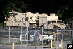 Military police stand military vehicles on a flat car in a rail yard, July 1, 2019, in Washington, ahead of a Fourth of July celebration that President Donald Trump says will include military hardware.