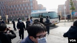 Los periodistas y el personal de seguridad se reúnen cerca de la entrada del Instituto Wuhan de Virología después de una visita del equipo de la OMS que se encuentra en Wuhan, en la provincia china de Hubei, el 3 de febrero de 2021.