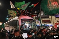 Kerumunan mengelilingi bus Palang Merah yang membawa tahanan Palestina yang dibebaskan dari penjara Israel dengan imbalan sandera yang dibebaskan oleh Hamas dari Jalur Gaza, di Ramallah di Tepi Barat yang diduduki pada awal 26 November 2023. (Foto: AFP)