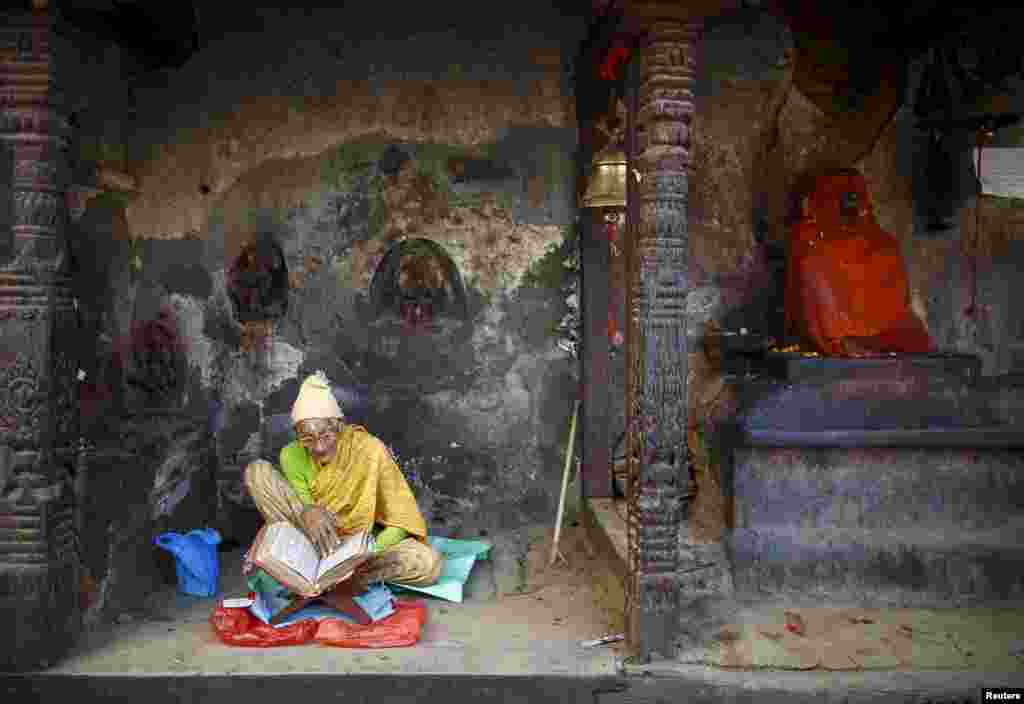 A woman reads a holy book as she sits in the remains of a temple after the earthquake in Kathmandu, Nepal.