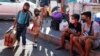 A young boy and girl hold hands as they arrive with their parents to try to catch a ride at the Cubao bus terminal in Manila, Philippines on Friday, March 13, 2020. 