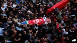Palestinian mourners carry the body of Omar Badawi, 22, during his funeral at the al-Arroub refugee camp in the West Bank city of Hebron, Nov. 11, 2019.
