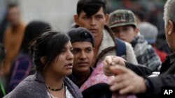 Migrantes escuchan las instrucciones mientras esperan en la fila una comida en un refugio en Tijuana, México, el miércoles 14 de noviembre de 2018.