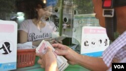 A man counts a stack of Cambodian riels in front of a currency exchange counter in Phnom Penh, Cambodia, on April 7, 2016. (Leng Len/VOA Khmer)