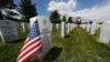 A flag stands next to the gravestone for a U.S. World War II veteran, at Fort Logan National Cemetery, in Sheridan, Colorado, May 23, 2020. 