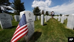 A flag stands next to the gravestone for a U.S. World War II veteran, at Fort Logan National Cemetery, in Sheridan, Colorado, May 23, 2020. 