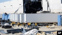 A workers walk outside a damaged warehouse after storms moved through Tuesday, March 4, 2025, in Lewisville, Texas.