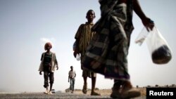 FILE - Ethiopian migrants walk on the side of a highway leading to the western Yemeni town of Haradh, on the border with Saudi Arabia.