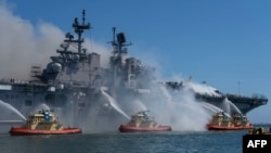 This U.S. Navy photo released July 13, 2020, shows sailors and federal firefighters battling a blaze onboard the amphibious assault ship USS Bonhomme Richard at Naval Base San Diego, California, July 12, 2020. (Christina Ross, U.S. Navy via AFP) 