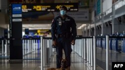 Un miembro de la Policía de Panamá controla la llegada de pasajeros de un vuelo humanitario hacia Fort Lauderdale en el Aeropuerto Internacional de Tocumen en la Ciudad de Panamá, el 8 de mayo de 2020.