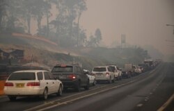 Cars line up to leave the town of Batemans Bay in New South Wales to head north, Jan. 2, 2020. A major operation to move people stranded in fire-ravaged seaside towns was under way in Australia after deadly bushfires ripped through tourist spots.