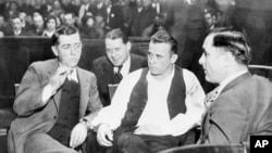 John Dillinger (center) was Public Enemy No. 1 in the 1930s. Here he is handcuffed and guarded in court as his trial date is set for March 12 at Crown Point, Ind., Feb. 9, 1934. (AP PHOTO)