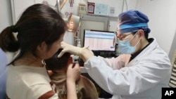 In this photo provided by researchers in January 2024, Dr. Yilai Shu examines a young patient at the Eye & ENT Hospital of Fudan University in Shanghai, China, after a gene therapy procedure for hereditary deafness. (Courtesy Dr. Yilai Shu via AP)