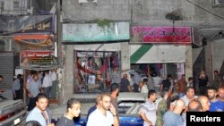 People gather around wreckage after a car bomb exploded in the Jaramana district of southeast Damascus, Aug. 6, 2013.