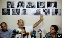 FILE - In this Wednesday, June 22, 2016 file photo, Egyptian lawyer and former presidential candidate Khaled Ali points to photos of jailed activists, who were arrested during protests over two disputed Red Sea islands, including Egyptian rights lawyer Malek Adly, top row third right, during a press conference, in Cairo, Egypt. An Egyptian court has ordered on Thursday, Aug. 25, 2016 the release of the prominent rights lawyer held in solitary confinement for the past three months after he challenged in court a decision by the country's president to hand over two Red Sea islands to Saudi Arabia.