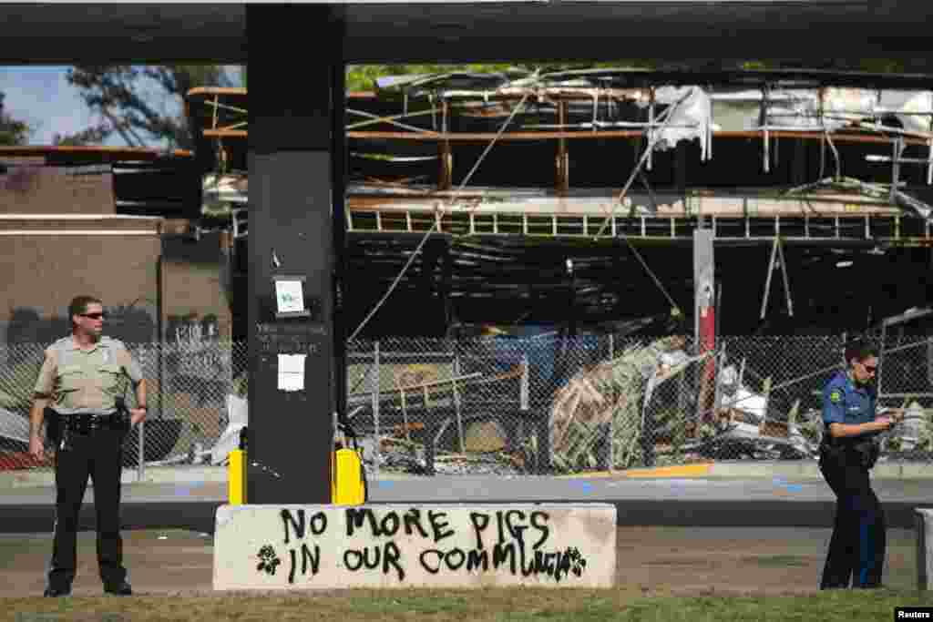 A police officer stands next to graffiti and a burned out Quick Time gas station in Ferguson, Missouri, August 18, 2014.