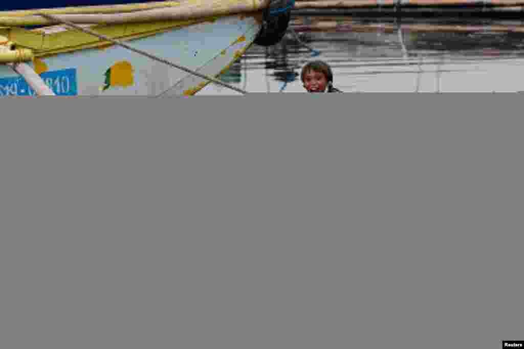 A boy reacts as dogs play along the riverbank of the Pasig River in Manila, Philippines.