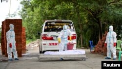 Volunteers wearing personal protective suits prepare to bury a body of a person who died from the coronavirus disease (COVID-19), at a cemetery in Yangon, Myanmar, October 17, 2020. REUTERS/Shwe Paw Mya Tin