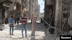 FILE - Residents inspect damages after an airstrike on the rebel held al-Maysar neighborhood in Aleppo, Syria, April 11, 2016. 