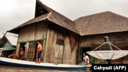 Warga menggunakan perahu untuk mengevakuasi keluarganya saat banjir melanda desa Sudan di Sampit, Kalimantan Tengah pada 23 Juli 2010. (Foto: AFP/Cahyadi)