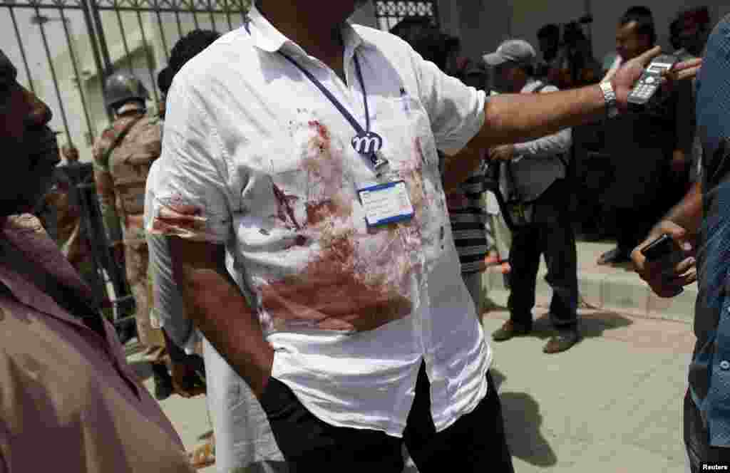 A hospital official wearing a bloodstained shirt stands outside the hospital where the victims of a shooting attack were transported, in Karachi, May 13, 2015.