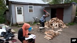 FILE - A girl studies for school while a man chops wood in the Muslim enclave of Islamberg in Tompkins, New York.