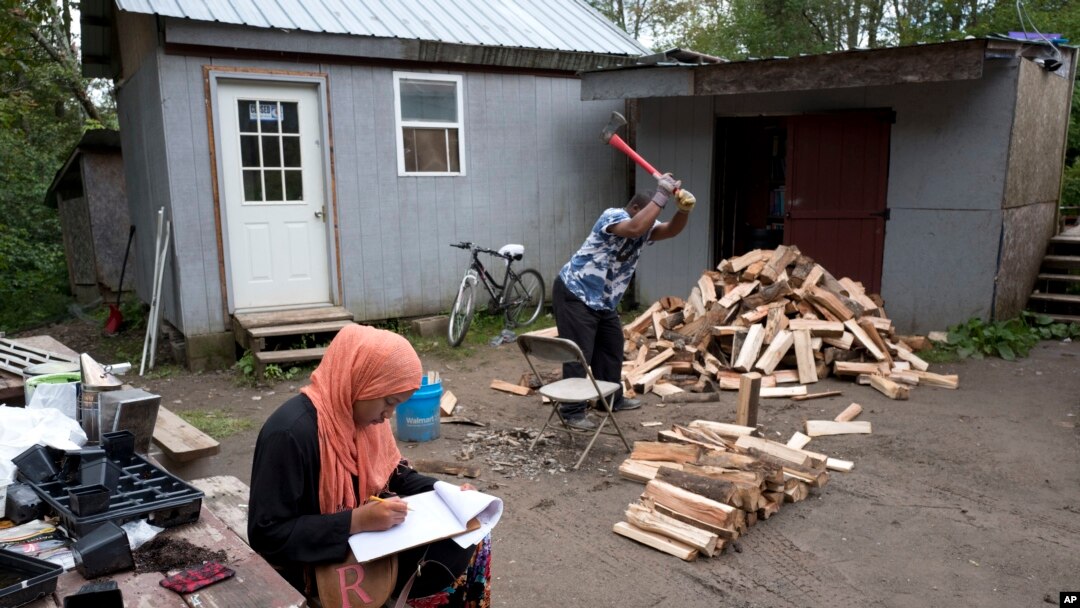 FILE - A girl studies for school while a man chops wood in the Muslim enclave of Islamberg in Tompkins, New York.
