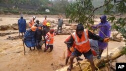 In this handout photo provided by the National Disaster Response Force (NDRF), NDRF personnel help move flood victims to safer areas in Wayanad district, in the southern Indian state of Kerala. 