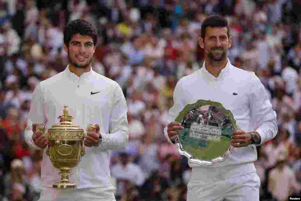 Petenis no. 1 dunia asal Spanyol, Carlos Alcaraz (kiri) berpose dengan trofi turnamen grand slam Wimbledon, setelah memenangkan pertandingan final melawan petenis Serbia Novak Djokovic di lapangan tennis All England di London, Inggris, Minggu 16 Juli 2023. (Reuters)&nbsp;