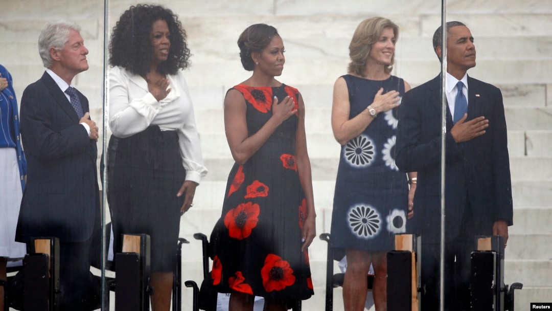 Former U.S. president Bill Clinton (L-R), Oprah Winfrey, U.S. first lady Michelle Obama, Caroline Kennedy, and U.S. President Barack Obama are pictured during the national anthem at a ceremony marking the 50th anniversary of Martin Luther King's "I have a