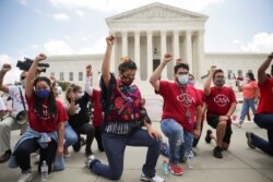 DACA recipients and their supporters take a knee in support of the Black Lives Matter movement, outside the U.S. Supreme Court in Washington, June 18, 2020.