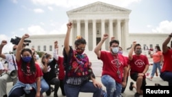 DACA recipients and their supporters take a knee in support of the Black Lives Matter movement, outside the U.S. Supreme Court in Washington, June 18, 2020.