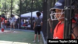 A young softball player on the South Bronx Red Wings awaits her turn at the dugout at the Harlem RBI field, in New York, Aug. 12, 2016.